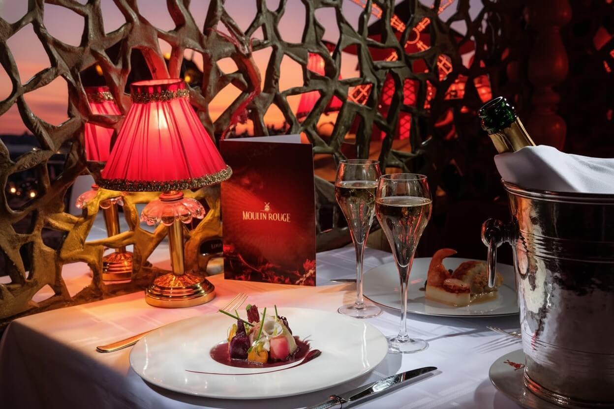 Mesa de cena en el Moulin Rouge con plato gourmet y champán